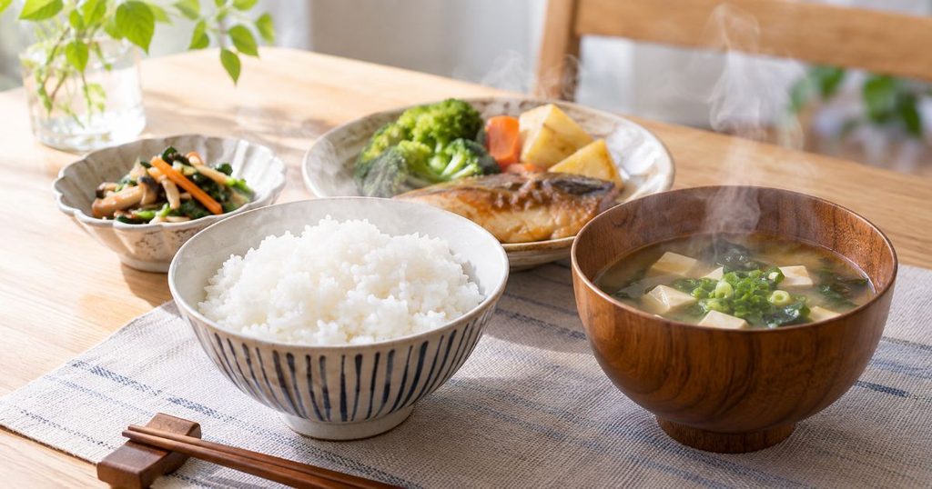 湯気の立つごはんと汁物、温めたおかずの食卓