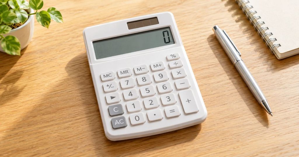 木製テーブルに置かれた電卓とペン