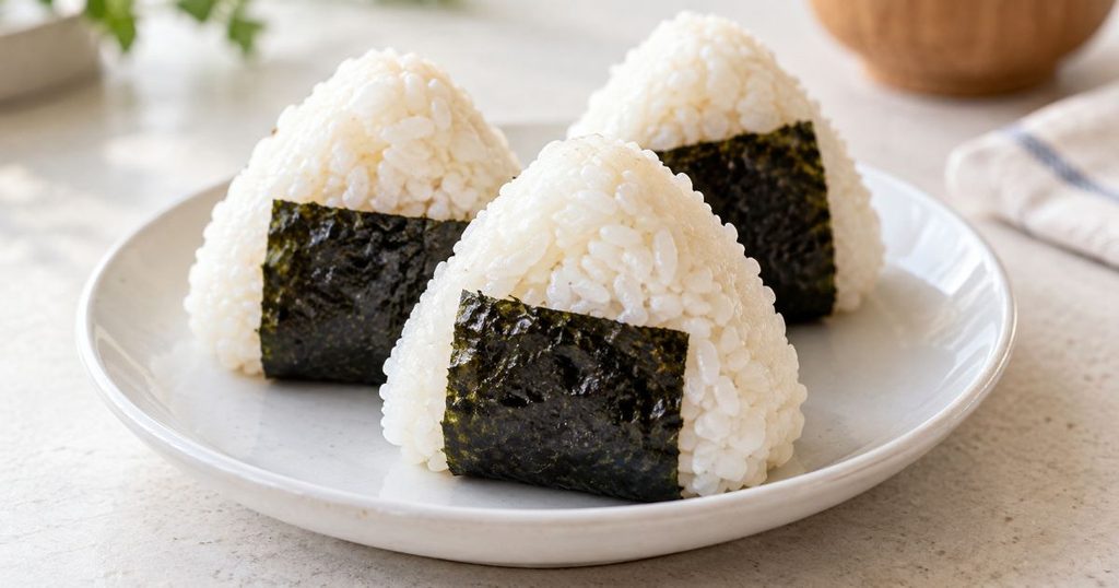 白い皿に盛り付けた海苔付きのおにぎり