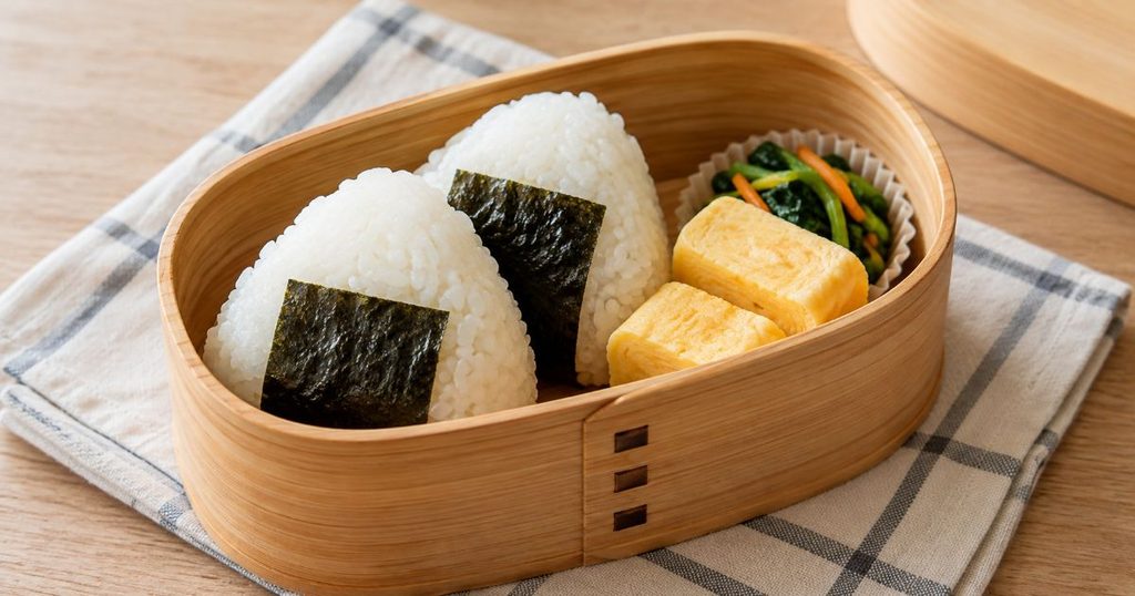おにぎりと卵焼きを詰めた木製弁当箱